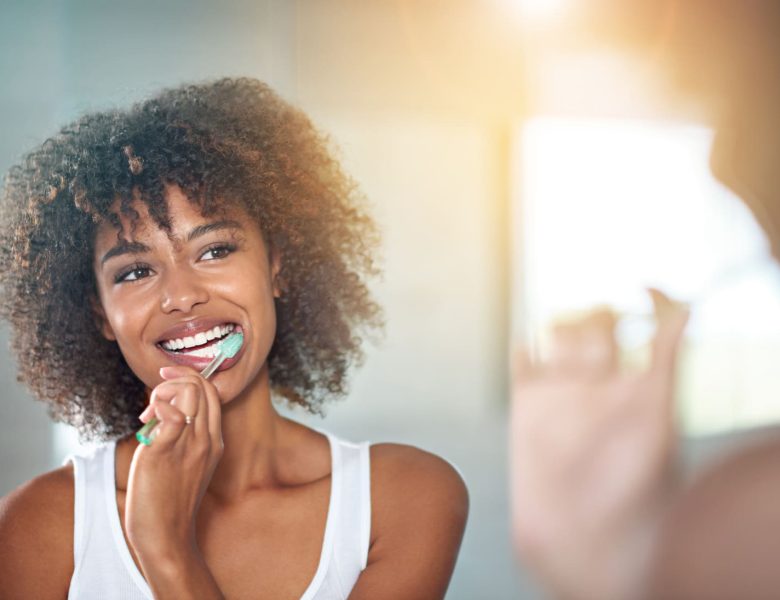 brossage des dents d'une jeune femme se brossant les dents dans la salle de bains.