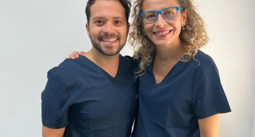 Dentiste français a l'étranger souriant tenant des instruments dentaires et une brosse à dents, prêt pour un examen oral.