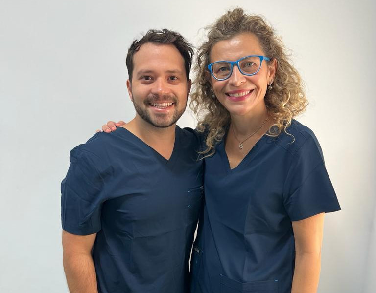 Dentiste français a l'étranger souriant tenant des instruments dentaires et une brosse à dents, prêt pour un examen oral.