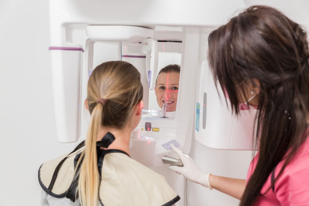 Une patiente recevant une radiographie dentaire numérique dans une clinique moderne tandis que le personnel dentaire supervise le processus.