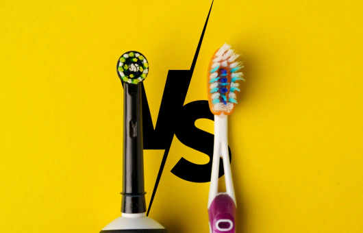 Comparaison entre une brosse à dents électrique et une brosse à dents manuelle sur fond jaune avec un 'VS' en arrière-plan.