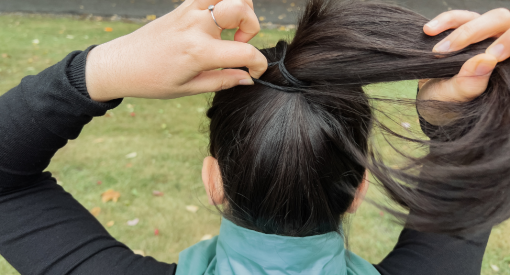 femme qui s'attache les cheveux en queue de cheval