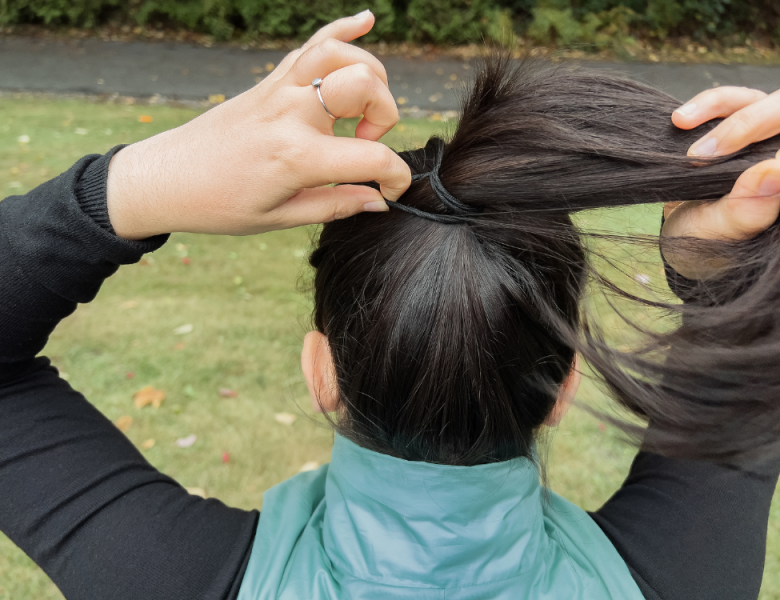 femme qui s'attache les cheveux en queue de cheval